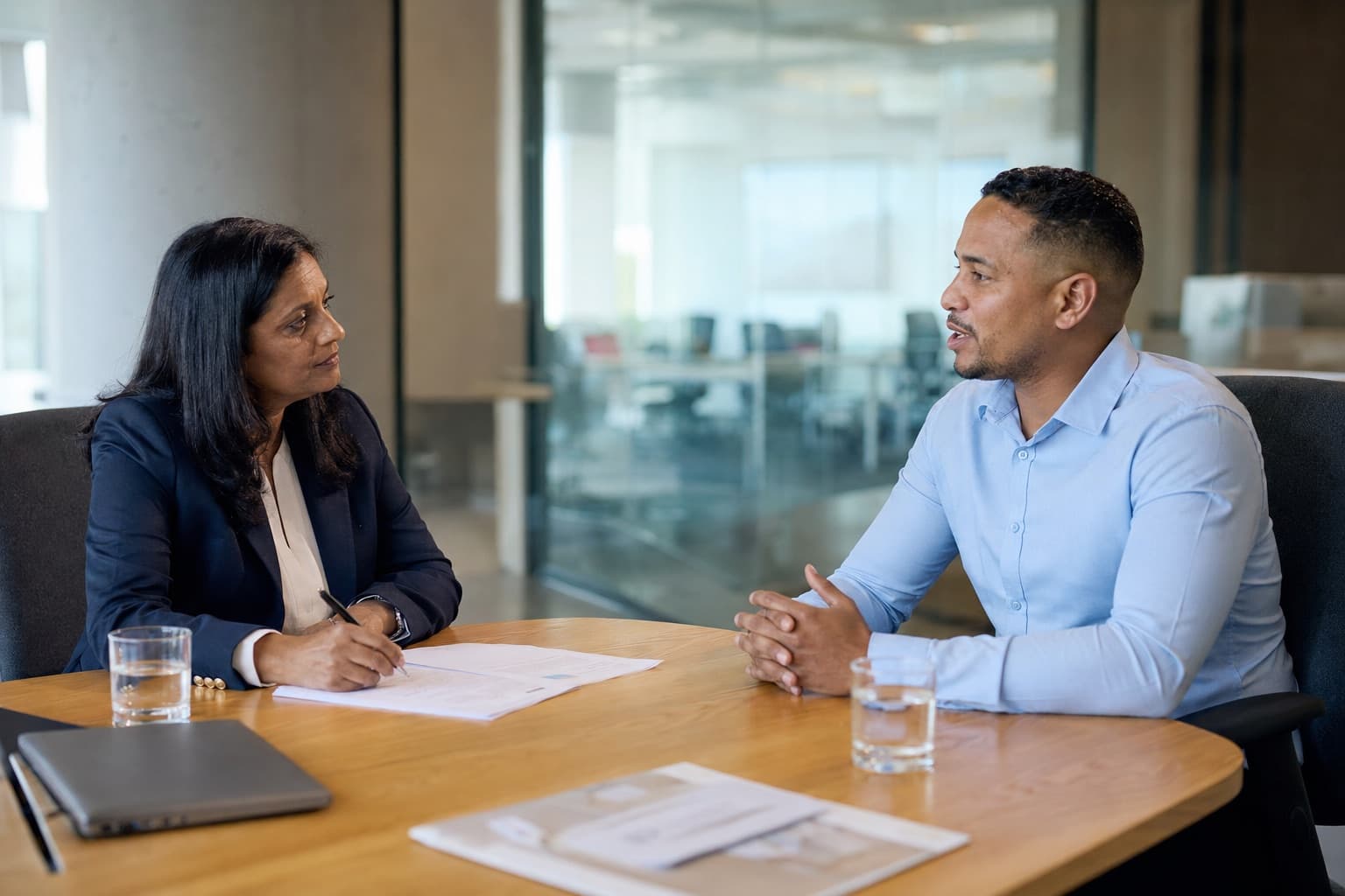 Hiring manager taking notes during a structured interview in a corporate meeting room